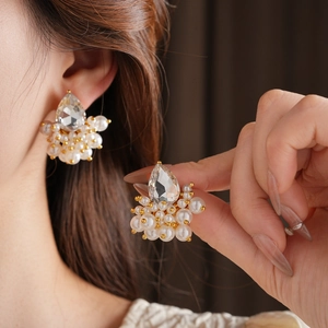 Macro view of French retro teardrop crystal and cluster pearl earrings with gold base
