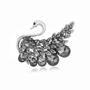 Macro detail of silver swan brooch featuring dark crystals and hanging teardrop gemstones