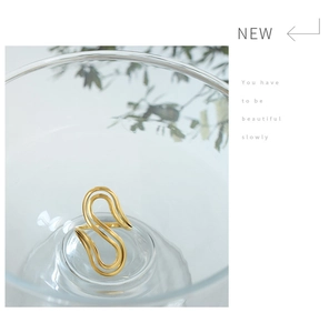 Detailed view of an S-shaped gold-plated open ring with smooth polished finish