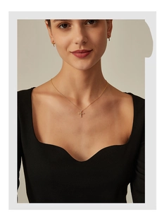 Detailed view of elegant gold cross necklace and matching zircon earrings set on model