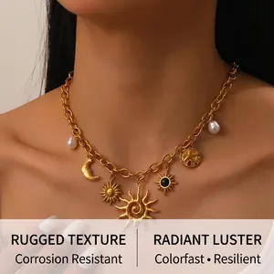 Détail de pendentifs soleil et lune dorés avec perles sur un collier à gros maillons