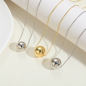 Detail of minimalist 14K gold and silver polished sphere pendants on box chains
