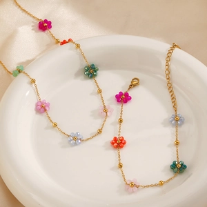 18K gold plated stainless steel necklace with colorful floral beads on ceramic plate