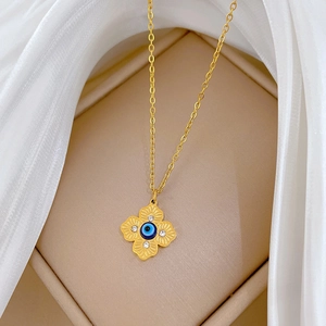 Close-up of gold clover necklace with blue evil eye bead in a jewelry box