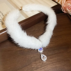 Macro shot of elegant white plush choker with sparkling teardrop crystal pendant