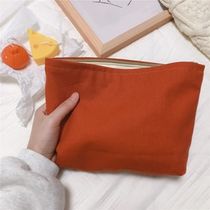 Detail of hand-held orange houndstooth cotton canvas pouch with zip closure