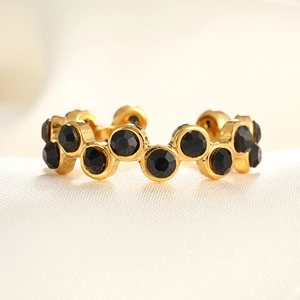 Close-up of golden wave ring with micro-pave black zircons on silk background