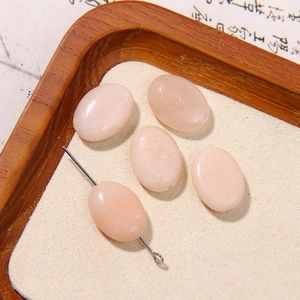 Macro detail of oval pink natural stone beads for DIY jewelry making on wooden tray