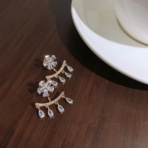 Elegant gold flower earrings with teardrop crystals on dark wood surface