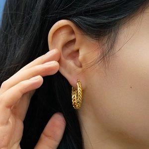 Gros plan d'une boucle d'oreille créole en or 18 carats avec motif d'épi sur un mannequin