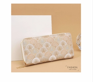 Detail of long beige clutch bag with golden shell embroidery and zipper closure