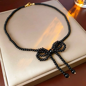 Detail of elegant black bead bow pendant necklace on a beige jewelry display case