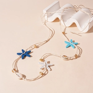 Detail of bohemian starfish and shell necklace on a wavy ocean-themed background