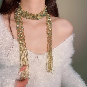 Close-up of elegant gold crystal beaded tassel necklace worn over a white fuzzy sweater