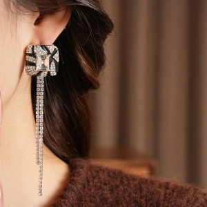 Close-up of geometric tassel earrings with rectangular crystals and silver chains