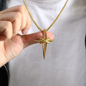 Macro detail of golden star cross pendant featuring intricate knot design on a chain