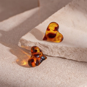 Macro shot of heart-shaped leopard resin earrings with vintage amber texture on stone