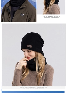 Detail of black knitted beanie and neck warmer set with brown embossed leather patch