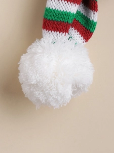 Close-up of a festive Christmas dog scarf with red green stripes and a soft plush white pompom