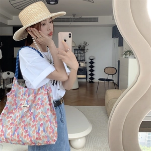 Mirror selfie showing floral tote bag with tulip print and blue fabric handles