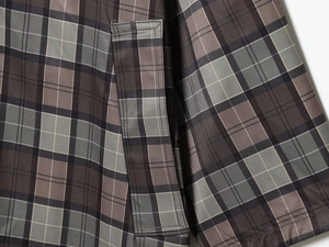 Detailed close-up of dark grey plaid fabric texture and neat stitching on a women's coat