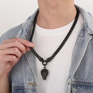 Detail of a black Cuban link necklace with a wolf head pendant worn by a male model