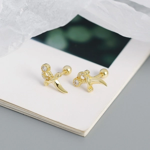 Detailed close-up of gold dagger earrings with sparkling crystals and screw back ball