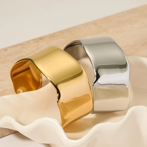 Minimalist wide gold and silver stainless steel bangles with irregular texture in a tray