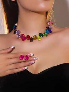 Detail of colorful crystal gemstone necklace and magenta earrings set on a model