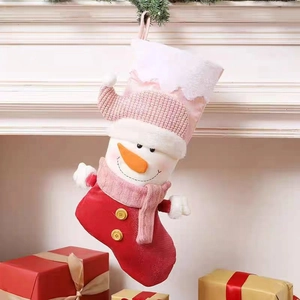 Calza di Natale con pupazzo di neve e sciarpa rosa appesa vicino al caminetto