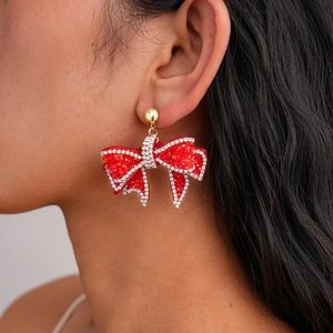 Close-up of elegant oversized red rhinestone bow earrings with silver trim on a model
