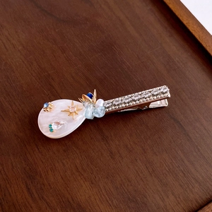 Detail of floral hair clip with crystal accents and gold alloy base on wooden texture