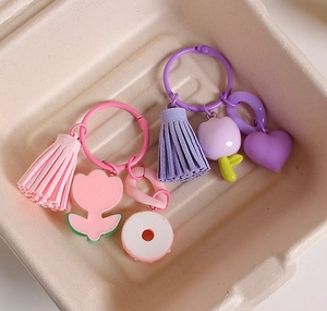 Detail of tulip resin keychains with tassels and macaron charms in pink and purple colors