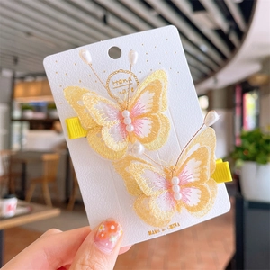 Detail of yellow embroidered butterfly hair clips with white pearls for kids