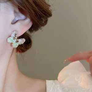 Close-up of sweet butterfly stud earrings with pink and green crystals on model