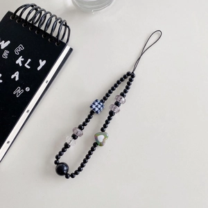 Detail of beaded phone strap with houndstooth cube and iridescent heart charm
