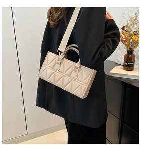 Detail of off-white geometric quilted handbag with wide fabric strap and PU leather texture