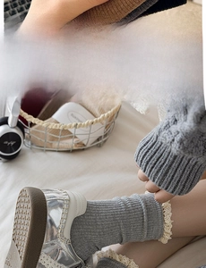 Detail of grey ribbed knit socks featuring delicate cream lace trim and vertical texture