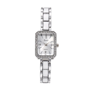 Close-up of square silver watch dial with crystal bezel and white ceramic bracelet