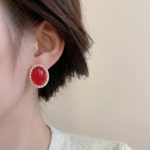 Boucles d'oreilles vintage rouges ovales avec perles et monture dorée sur un mannequin
