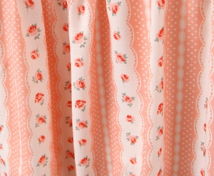 Dettaglio ravvicinato del tessuto in chiffon rosa con rose rosse e motivi in pizzo