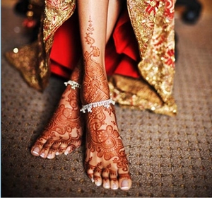 Close-up of brown henna lace tattoo stickers and silver anklets on a woman's feet