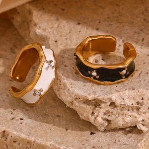 Macro view of gold-plated irregular rings with black and white enamel and tiny crystals
