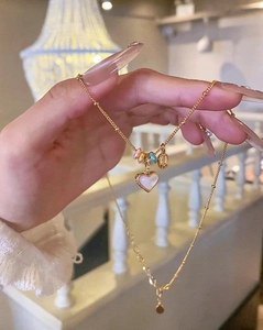 Detail of 18k gold plated necklace featuring white heart pendant and colorful rings