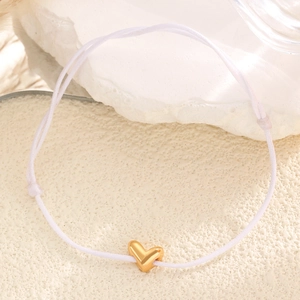 Macro d'un bracelet en corde blanche avec un charm coeur doré en 3D poli de haute qualité