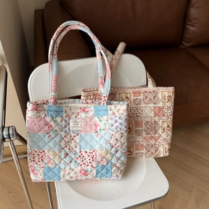 Detail of vintage floral quilted tote bags with French labels on a white wooden chair
