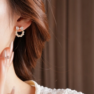 Vue détaillée de boucles d'oreilles nœud et couronne de perles avec zircons sur l'oreille