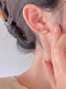 Detail of gold shell stud earrings on model with retro minimalist marine design