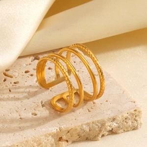 Minimalist gold multi-layered textured open ring displayed on stone with silk background