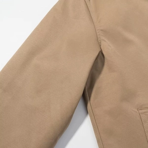 Close-up of khaki cotton twill fabric texture and stitching detail on women trench coat